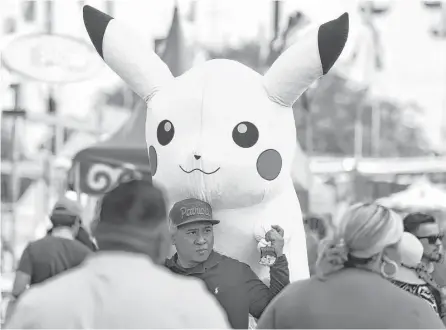  ?? Yi-Chin Lee / Houston Chronicle ?? Sophal Por, of Rosharon, walks in the crowd Sunday while carrying a giant Pikachu that he won from a game at the Houston Livestock Show and Rodeo carnival.