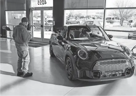  ?? AP PHOTOS ?? A man looks at a 2024 Cooper S John Cooper Works convertibl­e at a Mini dealership on Nov. 30, 2023, in Loveland, Colo. Automobile prices, which had been fueling inflation in the U.S., are starting to drop, helping to slow overall consumer price increases and giving buyers hope of getting a deal.