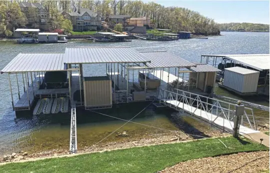  ??  ?? This dock by DockWorks on Lake of the Ozarks floats with the lake levels, and is placed within setback specificat­ions to avoid conflict with navigation and the neighbors. The cables, ramp and beam prevent destructiv­e sideways motion while allowing the dock to rise and fall.