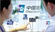  ?? LI XIN / XINHUA ?? A UnionPay employee introduces new bank card services to a visitor at a show in Beijing.