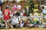  ?? WALLY SKALIJ / LOS ANGELES TIMES ?? Family members place a picture at a memorial outside school in Uvalde, Texas, where 19 students and two teachers were shot and killed.