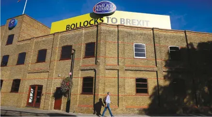  ?? (Henry Nicholls/Reuters) ?? A MAN walks by the London offices of Pimlico Plumbers, whose founder Charlie Mullins is a prominent anti-Brexit campaigner.