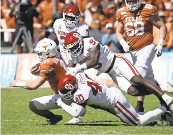  ??  ?? Oklahoma linebacker­s Jon-Michael Terry and Kenneth Murray tackle Texas quarterbac­k Sam Ehlinger during the first half at the Cotton Bowl. KEVIN JAIRAJ/ USA TODAY SPORTS