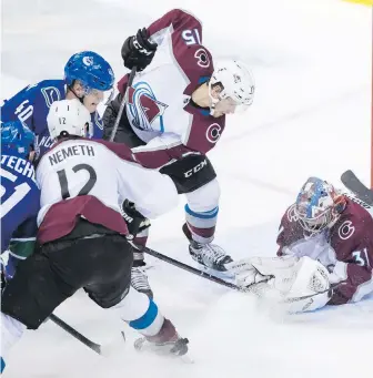  ?? CP ?? Squeezed between Colorado’s Patrik Nemeth (12) and Sheldon Dries (15), the Canucks’ Elias Pettersson (40) beats Avalanche goalie Philipp Grubauer (31) for a second-period goal Friday night in Vancouver. The Canucks’ Troy Stecher (51) helps fend off Nemeth. The Canucks won 7-6 in overtime.