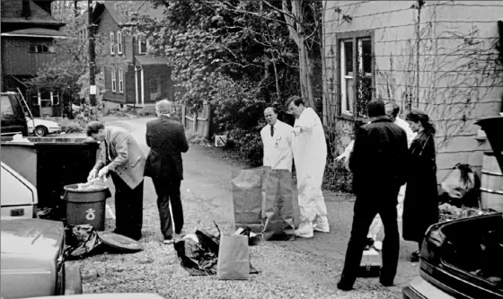  ?? Courtesy of William P. Mullen ?? William P. Mullen, left, then a Pittsburgh police lieutenant, searches for body parts in a Shadyside garbage can May 4, 1992.