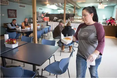  ?? Staff photo by Evan Lewis ?? n Kim Winfield, co-owner of Ko-Fields Diner in Prescott, Ark., brings lunch to one of the customers Wednesday. Winfield, a Prescott High graduate and former cheerleade­r, said Curley Wolves football is a common topic of discussion in the smalltown eatery.