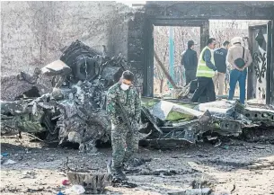  ?? ARASH KHAMOOSHI THE NEW YORK TIMES ?? A security official examines wreckage of the Ukraine Internatio­nal Airlines crash in Tehran. There are reports that Iranian authoritie­s are refusing to share flight data with western investigat­ors.