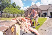  ?? MAX BECHERER/ASSOCIATED PRESS ?? Jody Harelson, 52, dumps a wheelbarro­w of wet sheet rock on an ever-growing pile of rubbish as he helps clean out the flood-damaged home of Sheila Seiner, 58, in St. Amant, La.