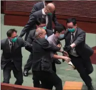  ??  ?? Pro-democracy lawmaker Ted Hui, centre, struggles with security guards in the Legislativ­e Council in Hong Kong during a debate on a bill to criminaliz­e insulting the Chinese anthem