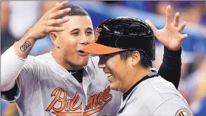  ?? FRANK GUNN/THE CANADIAN PRESS VIA AP ?? Baltimore’s Hyun Soo Kim, right, is congratula­ted by Manny Machado after Kim hit a pinch-hit home run in the ninth inning of the Orioles’ win over the Blue Jays on Wednesday.