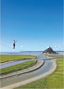  ?? AFP-Yonhap ?? Frenchman beats high-wire record
French tightrope walker Nathan Paulin walks on a slackline in the bay of Le Mont Saint-Michel, north-western France, Tuesday. Paulin claimed a new world record as he completed a 2,200-meter-long (nearly 1.4-mile) trip to Mont Saint-Michel along a wire suspended between a crane and the famous abbey on the tidal island.