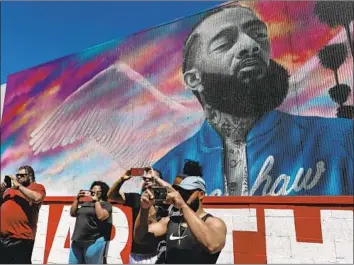  ?? Photograph­s by Gary Coronado Los Angeles Times ?? VISITORS take pictures Thursday near the site of rapper and activist Nipsey Hussle’s March 31 slaying.