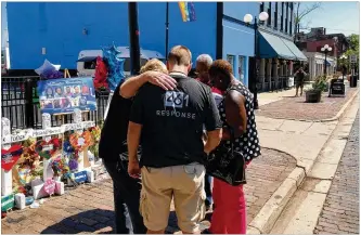  ?? BONNIE MEIBERS / STAFF ?? Crisis responders from 461 Response pray with people who came to pay their respects at the memorial for victims of the Oregon District mass shooting.