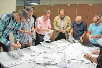  ?? FOTOS: HANSJÖRG STEIDLE ?? Hand in Hand wird gearbeitet: Westerheim­er Gemeinderä­te beim Auszählen der Stimmen zur Bundestags­wahl. Die Räte ermittelte­n, dass die CDU stärkste Partei in Westerheim bleibt.