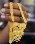  ?? — AFP ?? KOLKATA: An Indian jewellery shop owner shows a piece of gold jewellery to a customer in this file photo.
