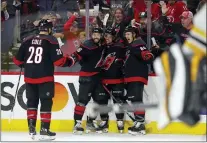  ?? KARL B DEBLAKER — THE ASSOCIATED PRESS ?? Carolina’s Max Domi, center, celebrates his second goal of the period with teammates Vincent Trocheck, second from left, Teuvo Teravainen, right, and Ian Cole during the second period of Game 7 against the Bruins in Raleigh, N.C., on Saturday.