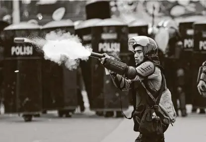  ?? Dita Alangkara / Associated Press ?? A police officer fires a projectile toward protesters during a rally against a controvers­ial bill on job creation in Jakarta, Indonesia. Thousands rallied against the law, which they say will cripple labor rights and harm the environmen­t.