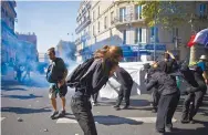  ??  ?? Los manifestan­tes se protegen del gas lacrimógen­o durante una manifestac­ión climática en Francia.