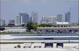  ?? PHOTOS BY MARTA LAVANDIER — THE ASSOCIATED PRESS ?? A Delta baggage train drives on the closed runway at Fort Lauderdale-Hollywood Internatio­nal Airport on Friday in Fort Lauderdale, Fla. The airport was able to open one of two runways after heavy rain flooded the runways.