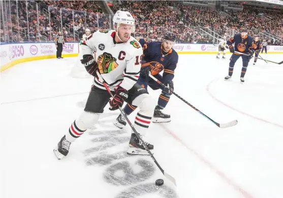  ?? JASON FRANSON/AP ?? Blackhawks captain Jonathan Toews shields the puck from Oilers defenseman Kris Russell during the first period Saturday in Edmonton, Alberta.