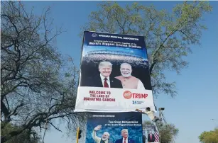  ?? (Adnan Abidi/Reuters) ?? A WORKER INSTALLS a billboard yesterday with the images of India’s Prime Minister Narendra Modi and US President Donald Trump along a road in Ahmedabad ahead of Trump’s visit.