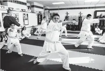  ?? Brett Coomer / Staff photograph­er ?? Vincente Vasquez, center, participat­es in Roy White’s karate class at Burbank Middle School. White believes karate provides an outlet for kids facing academic, family and social pressures.