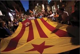  ??  ?? In this photo taken on Sept. 10, people demonstrat­e carrying “esteladas” or independen­ce flags ahead of the Catalan National Day in Barcelona, Spain. A confrontat­ion between the central government in Madrid and independen­ce movements in the wealthy...