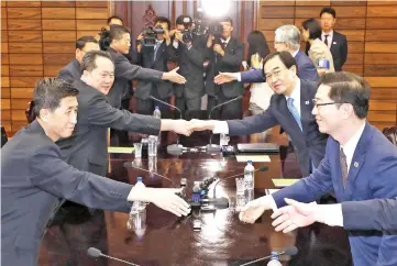  ?? — AFP photo ?? Cho (second right) shakes hands with Ri (second left) at the end of their talks at the North side of the border truce village of Panmunjom in the Demilitari­sed Zone (DMZ).