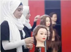  ?? — Reuters ?? A woman practices on hair mannequins at a training salon in Bar Elias town, in the Bekaa valley, Lebanon.