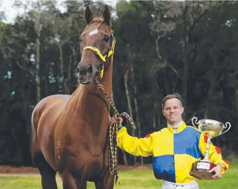  ?? Picture: STEWART McLEAN ?? HIGH HOPES: Trevor Rowe stable jockey John Lambie with the Cairns Newmarket Cup that he’ll be out to win today on Stable Surprize.