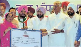  ?? PARDEEP PANDIT/HT ?? CM Capt Amarinder Singh and state Congress president Sunil Jakhar along with ministers handing over a nodue certificat­e to a woman to waive loans of Scheduled Castes and Backward Classes, in Jalandhar on Saturday.