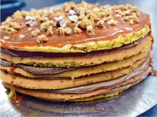  ?? Fotos: Marcus Merk ?? Sogenannte Naked Cakes sind eine Spezialitä­t im Meitinger Café Contur. Die Schoko-Knusper-Karamell-Torte besteht aus sechs einzeln gebackenen Biskuit-Krokant-Böden, dazwischen ist eine Schoko-Karamell-Buttercrem­e. Eine Zuckerglas­ur oder ein Sahnekleid...