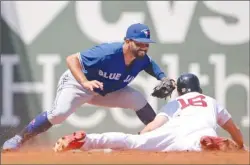  ?? The Associated Press ?? Toronto Blue Jays second baseman Devon Travis tags out Andrew Benintendi (16) of the Boston Red Sox during third-inning AL action at Fenway Park on Wednesday in Boston. The Blue Jays lost 6-4.