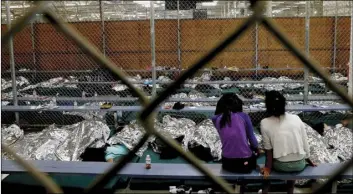  ??  ?? In this June 18, 2014, file photo, two young girls watch a World Cup soccer match on a television from their holding area where hundreds of mostly Central American immigrant children are being processed and held at the U.S. Customs and Border...