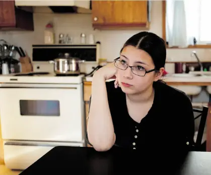  ??  ?? Flo Laboucan sits in the kitchen of her mother’s trailer in Cadotte Lake. Her high school education was interrupte­d