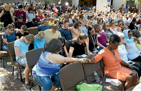  ?? PHOTO: WASHINGTON POST ?? People pray at Parkridge Church in Coral Springs, Florida during a vigil yesterday for the victims of the Marjory Stoneman Douglas High School mass shooting. Nikolas Cruz, the 19-year old former student accused of the massacre, has been charged with 17...