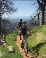  ??  ?? Rae Teeter of the North State Composite Mountain Bike team is trailed by head coach Dan Mauldin while riding on a trail.