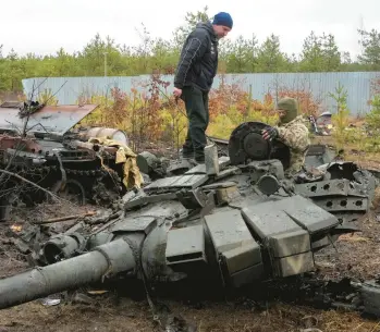  ?? EFREM LUKATSKY/AP ?? A Ukrainian soldier examines a Russian military vehicle on Saturday in the village of Dmytrivka, Ukraine.