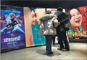  ?? DU LIANYI / CHINA DAILY ?? People look at movie posters at a theatre in Beijing on Feb 15.