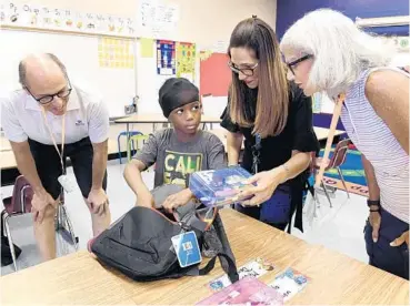  ?? TAIMY ALVAREZ/SUN SENTINEL ?? Boca West Children’s Foundation board member Richard Zenker, left, and his wife, far right, watch as Messiah Desir and his new teacher Alina Valdez look through his new school supplies donated by the foundation on Friday in Delray Beach.