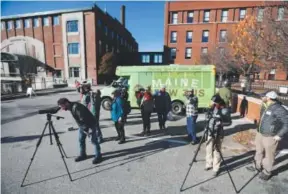  ??  ?? A group of birding enthusiast­s use spotting scopes to view a peregrine falcon on a distant church steeple after visiting the Baxter Beer brewery in Lewiston, Maine. The Maine Brew Bus tour group combines bird watching and visits to microbrewe­ries in...