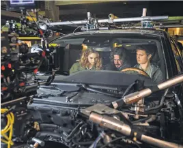 ??  ?? Director EdgarWrigh­t, center, works with Lily James and Elgort on set in the “biscuit” rig, which is used to get interior car shots with real- life conditions.