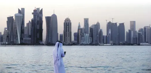  ??  ?? A man looks at his phone in the Qatari capital Doha, July 2.