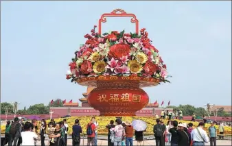  ?? FENG YONGBIN / CHINA DAILY ?? Tourists take photos of the huge flower basket arrangemen­t themed “Blessings to the Motherland” in Tian’anmen Square in Beijing on Thursday. The traditiona­l annual decorative work celebrates the upcoming National Day on Oct 1.