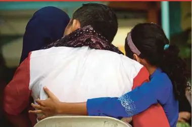  ?? PIC BY DANIAL SAAD ?? One of the inmates hugging his two daughters during the Hari Raya celebratio­n at the Penang Remand Prison in George Town yesterday.