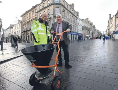  ?? Picture: Phil Hannah. ?? Perth and Kinross Council leader Ian Campbell tries out a push-along gritter with the help of Stuart D’All of the council’s roads maintenanc­e department, in Perth’s High Street.