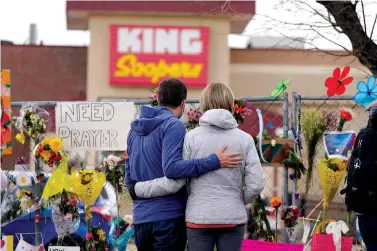  ?? The Associated Press ?? ■ Mourners walk the temporary fence line outside the parking lot of a King Soopers grocery store, the site of a mass shooting in which 10 people died Friday in Boulder, Colo.