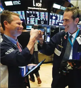  ?? (AP/Richard Drew) ?? Traders Robert Charmak (left) and Gregory Rowe bump fists Monday at the close of trading on the floor of the New York Stock Exchange, celebratin­g the stock market’s rebound after more than a week of heavy losses.