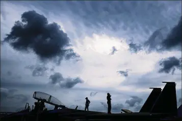  ?? YONG TECK LIM / ASSOCIATED PRESS ?? Singapore air force personnel stand atop an F-15 fighter jet Feb. 7 during the Singapore Airshow in Singapore. But the buzz at Asia’s largest air show this year was about unmanned aerial vehicles, or drones.