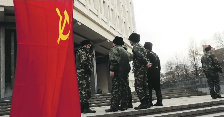  ?? Spencer Platt / Gett y Images ?? A Soviet flag flies outside the Ukrainian Parliament as dozens of Russian Cossacks surround the building in a show of support for Russia in Simferopol, Ukraine, on Thursday.